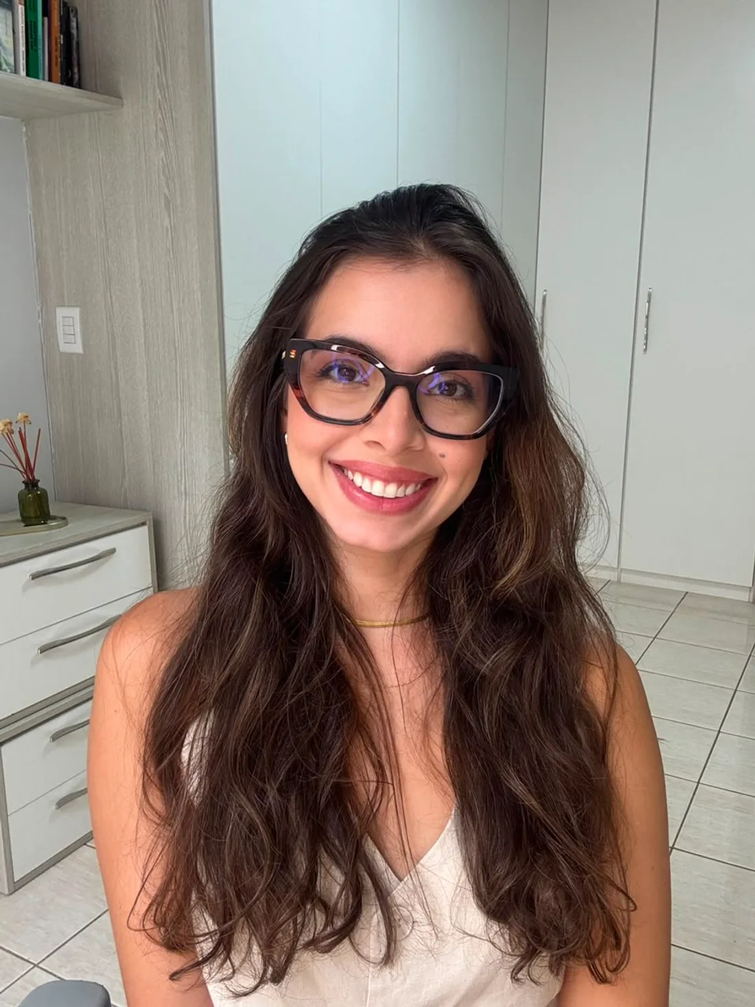 Julia Alcântara, professora de inglês, sorrindo no espaço onde dá as aulas online
